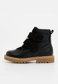 Schwarze Knöchelboots mit einem strukturierten Lederoberteil, zwei Klettverschlüssen, einem gepolsterten Knöchel und einer robusten, tanfarbenen Gummisohle.