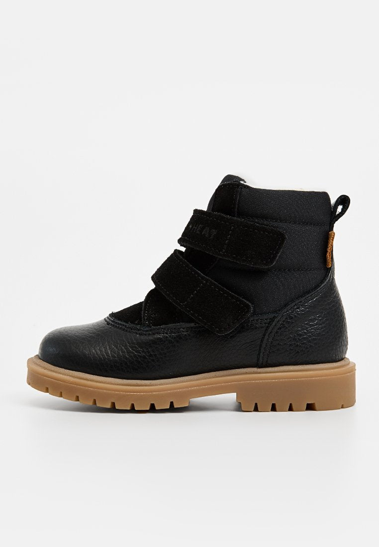 Schwarze Knöchelboots mit einem strukturierten Lederoberteil, zwei Klettverschlüssen, einem gepolsterten Knöchel und einer robusten, tanfarbenen Gummisohle.