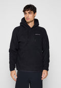 Mann trägt einen schwarzen Fleece-Kapuzenpullover mit Fronttasche und kleinem weißen Logo auf der Brust, steht vor grauem Hintergrund.