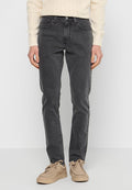 Graue Jeans aus Denim mit schlanker Passform, fünf Taschen-Design und dezentem Fade-Effekt. Kombiniert mit einem cremfarbenen Strickpullover und beigen Schuhen.