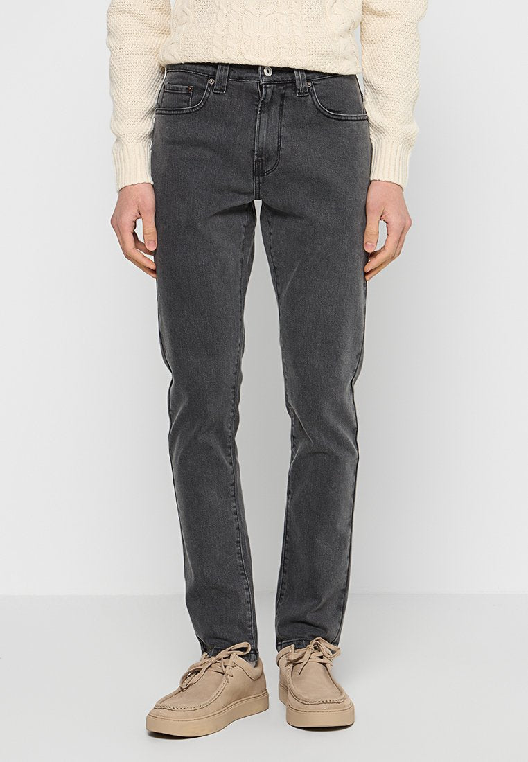 Graue Jeans aus Denim mit schlanker Passform, fünf Taschen-Design und dezentem Fade-Effekt. Kombiniert mit einem cremfarbenen Strickpullover und beigen Schuhen.