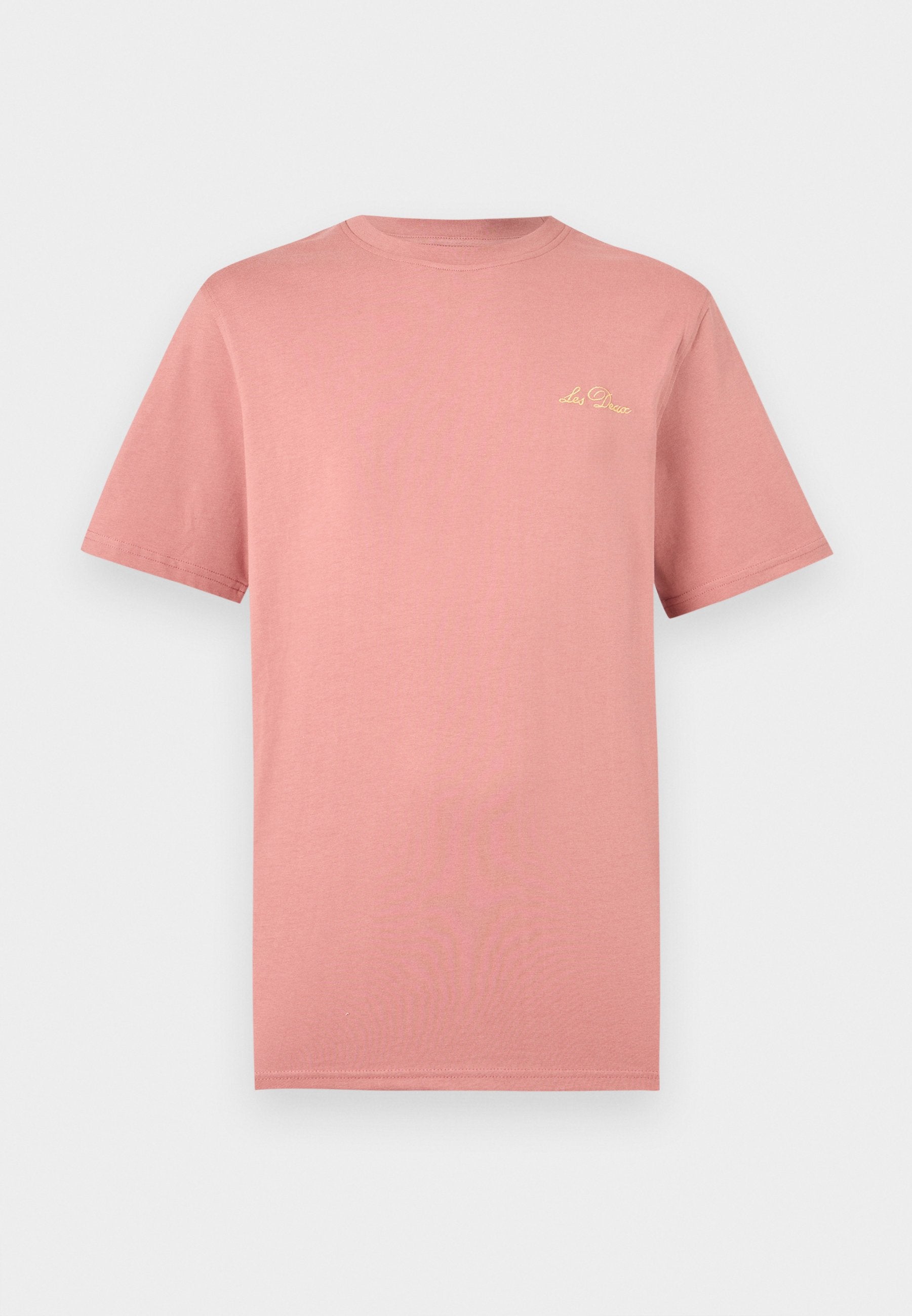 Schlichtes, gedämpftes rosa T-Shirt mit kurzen Ärmeln und kleinem gelbem, kursivem "Les Deux"-Logo auf der oberen linken Brust vor weißem Hintergrund.