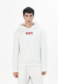Mann in weißem Hoodie mit rotem Diesel-Logo, weißen Hosen, steht vor einem schlichten weißen Hintergrund und blickt nach vorne.