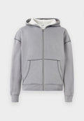 Grauer Hoodie mit Reißverschluss, Fronttaschen, gerippten Bündchen und Saum, strukturiertem weißen Innenfutter und kontrastierenden Detailnähten.
