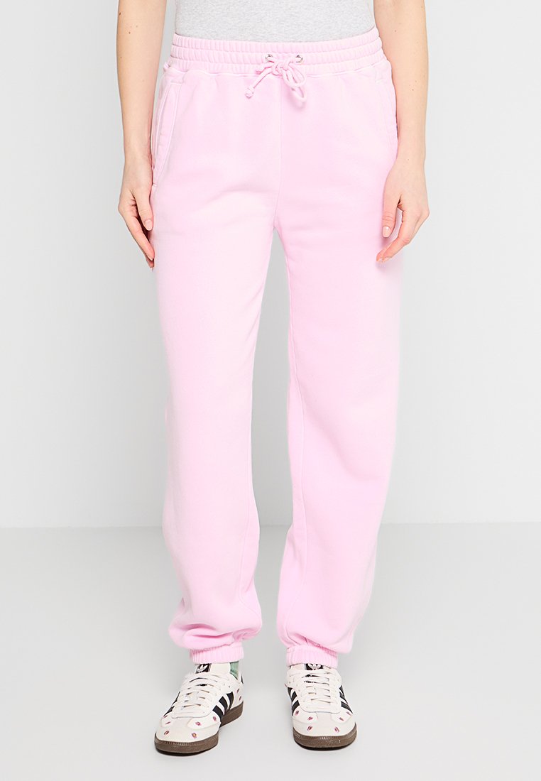 Helle rosa Jogginghose mit einem elastischen Taillenbund und Kordelzug, ausgestattet mit seitlichen Taschen und gerippten Bündchen. Hergestellt aus weichem, strukturiertem Stoff.