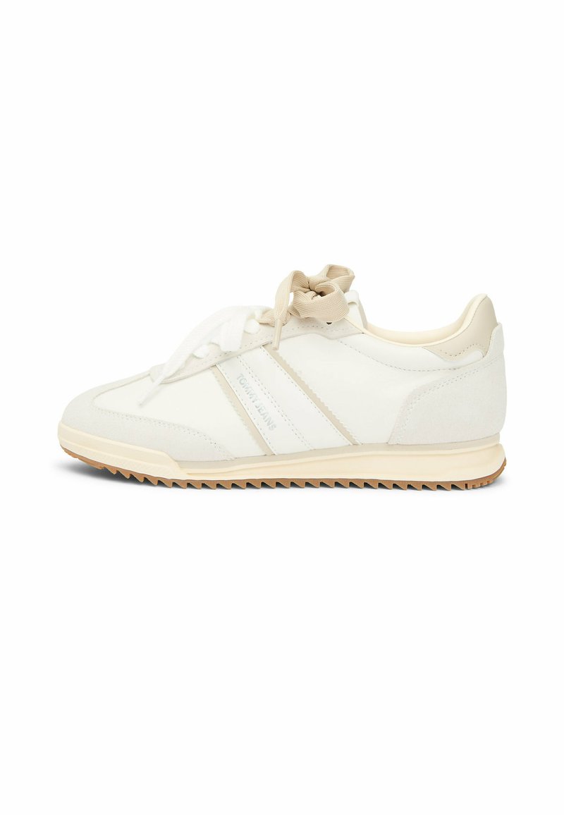 Weißer Sneaker mit niedrigem Schaft, beiger Sohle, cremefarbenen Akzenten und beigen Schnürsenkeln, die zu einer Schleife gebunden sind, Seitenansicht nach rechts auf weißem Hintergrund.