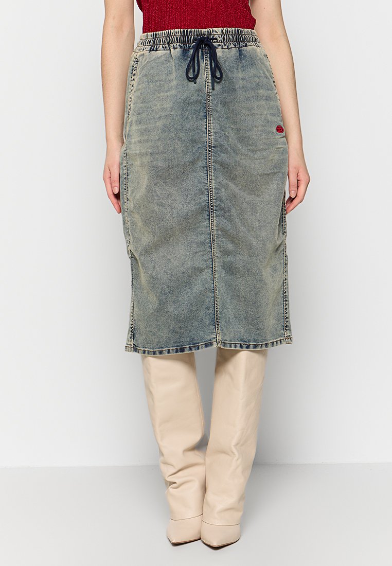 Hellblaue Jeans-Midirock mit elastischem Bund, Kordelzug-Detail und Seitentaschen. Kombiniert mit knielangen beigen Stiefeln.