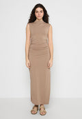 Beige ärmelloses Maxikleid mit tailliertem Oberteil und geraffter Taille. Weicher, glatter Stoff mit geradem Schnitt. Ein Paar braune Sandalen getragen.
