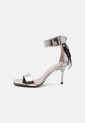 Metallic silberne offene High-Heel-Sandalette mit Knöchelriemen und Schnalle, verziert mit einer dekorativen Schleife hinten.