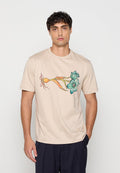 Junger Mann mit kurzem dunklem Haar, der ein beiges T-Shirt mit einem bunten botanischen Design mit blauen Blumen und einer orangefarbenen Knolle trägt.