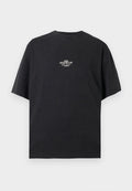 Schwarzes T-Shirt mit kurzen Ärmeln und Rundhalsausschnitt mit kleinem weißen Text "Pegador" zentriert auf der Brust vor einfarbigem Hintergrund.