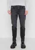Schwarze Denim-Jeans mit schlankem Schnitt, ausgestattet mit Fronttaschen, dezenten Nähten und einem Knopfverschluss. Tragen mit schwarzen Stiefeln.