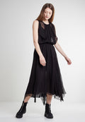 Schwarzes, ärmelloses Kleid mit einem fließenden, gestuften Design und durchsichtigen Lagen sowie einer taillierten Taille. Kombiniert mit schwarzen, Reißverschluss-Ankle Boots.