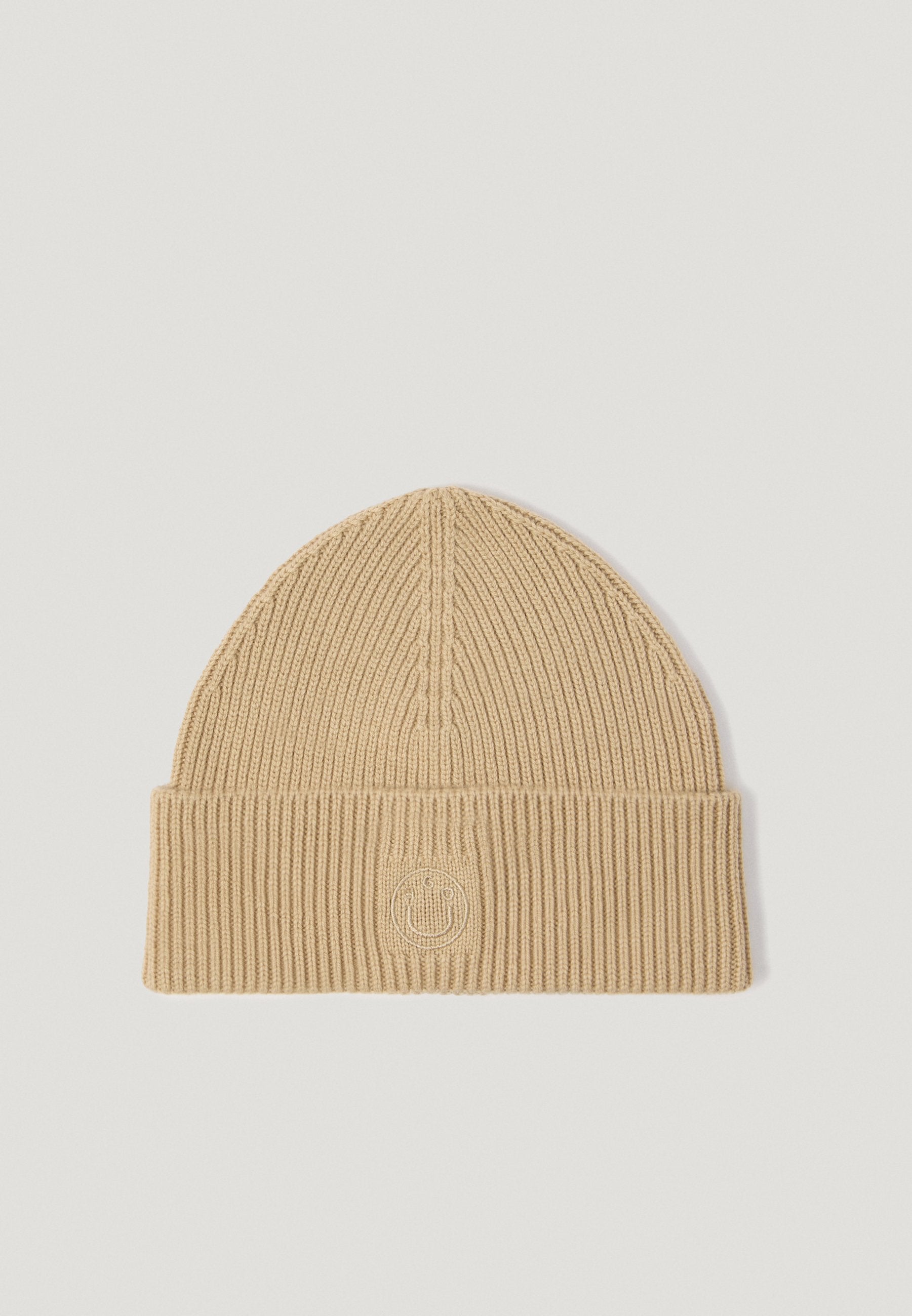 Strickmütze in Lichtbeige mit gerippter Textur und umgeschlagenem Bündchen. Hat ein kreisförmiges, geprägtes Logo auf der Vorderseite.