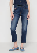 Frau trägt dunkelblaue Denim-Jeans und ein passendes ärmelloses Denim-Top, kombiniert mit hellblauen Mary Jane Ballerinas.