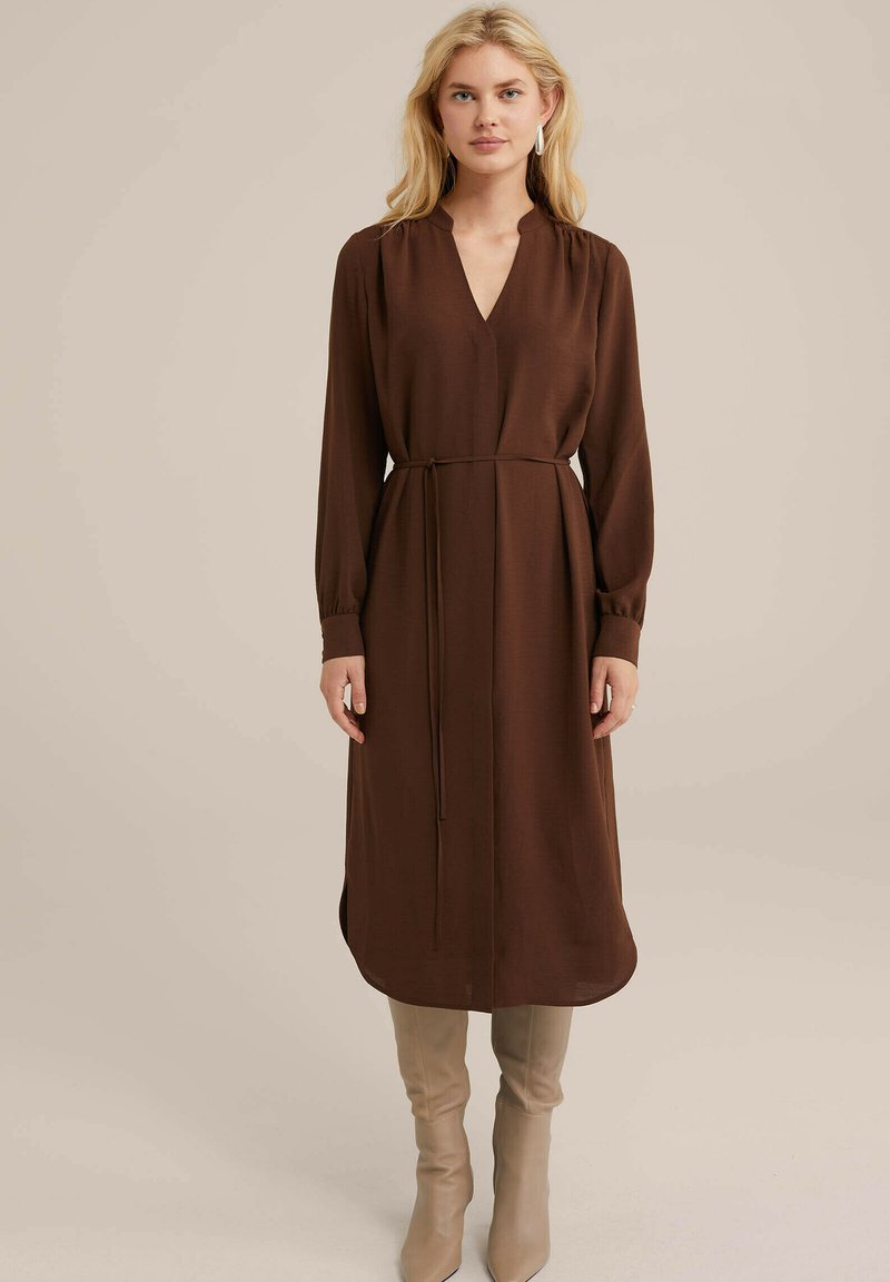 Braunes, langärmeliges Kleid mit V-Ausschnitt, gerafften Schultern und einem gebundenen Taillenband. Glattes Material mit gerader Silhouette und seitlichen Schlitzen.
