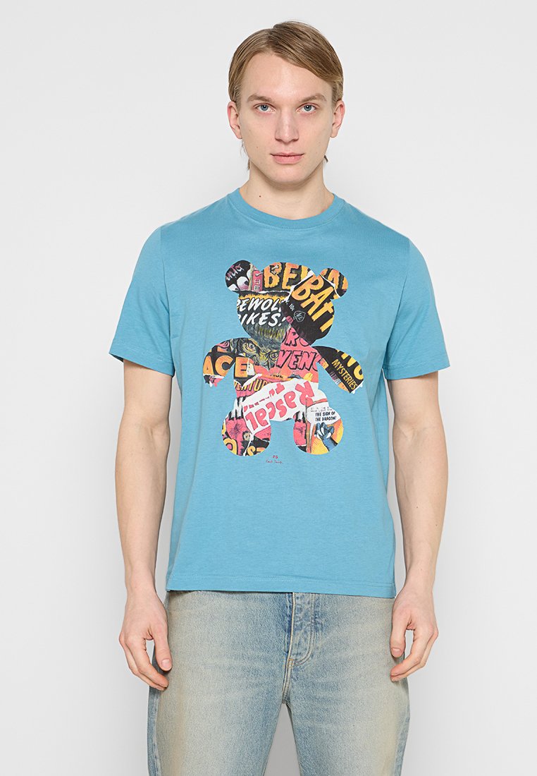 Türkisfarbenes Baumwoll-T-Shirt mit einem Bärenmotiv, das aus buntem Text und Mustern besteht. Kurzärmlig, Rundhalsausschnitt.