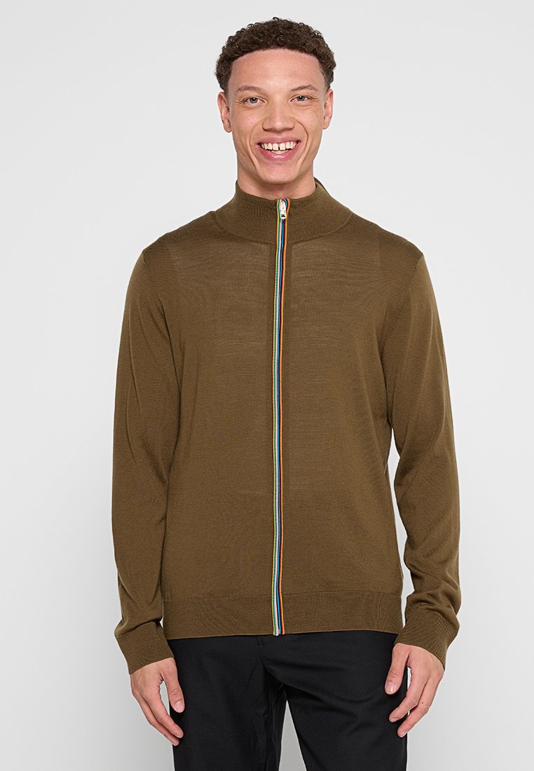 Brauner Reißverschluss-Pullover mit hohem Kragen, der einen mehrfarbigen Streifen entlang des Reißverschlusses aufweist. Strickstruktur und enganliegendes Design.