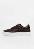 Brauner Ledersneaker mit abgerundetem Zehenbereich, tonalen Schnürsenkeln und einer strukturierten weißen Gummisohle. Mit minimalem Branding an der Seite.