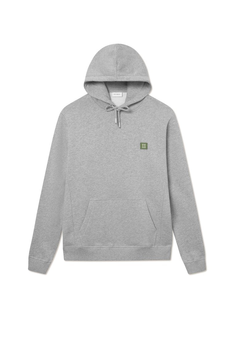 Grauer Kapuzenpullover aus weichem Material, mit einer Fronttasche und einem kleinen grünen Patch mit dem "II"-Logo auf der linken Brustseite.