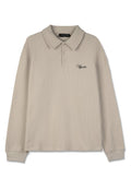 Beige Langarm-Polohemd aus strukturiertem Waffelstrickstoff, mit klassischem Kragen, drei Knöpfen und einem schwarzen Logo-Akzent.
