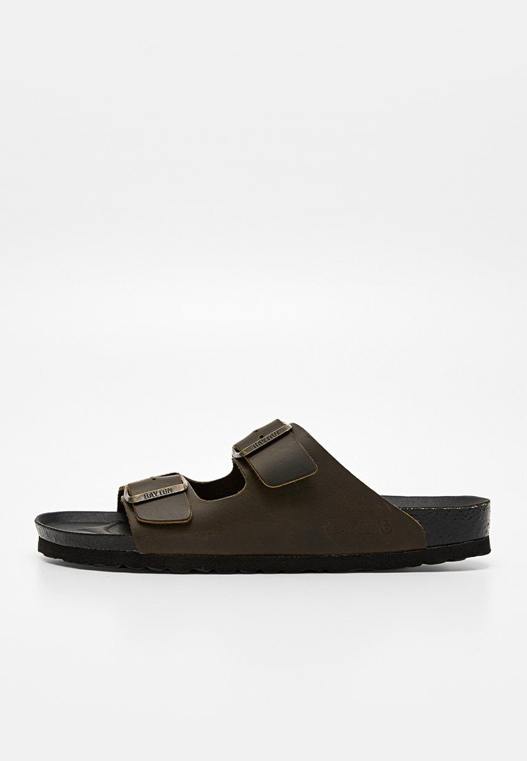 Dunkelbraune Slipper-Sandale mit zwei verstellbaren Schnallenriemen und einer schwarzen, konturierten Sohle, seitlich auf weißem Hintergrund abgebildet.