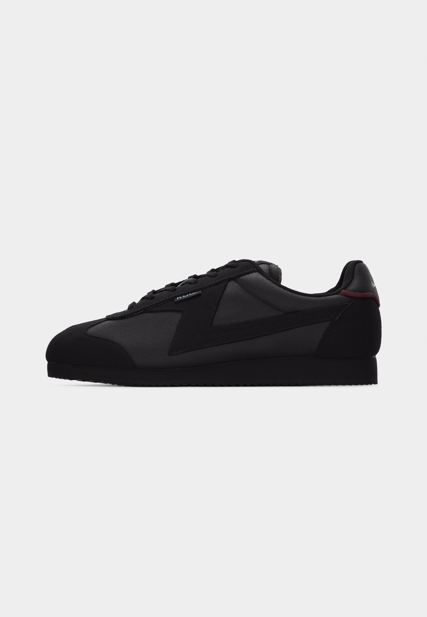 Schwarzer Sneaker in Low-Top-Design mit Schnürung vorne, glatten und Wildlederpaneelen sowie strukturierter Sohle vor weißem Hintergrund.