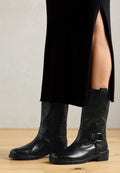 Schwarze Leder-Stiefel bis zum Knie mit runder Spitze, glatter Oberfläche, flachem Absatz, seitlichem Reißverschluss und einem verstellbaren Riemen mit Schnallen-Detail.