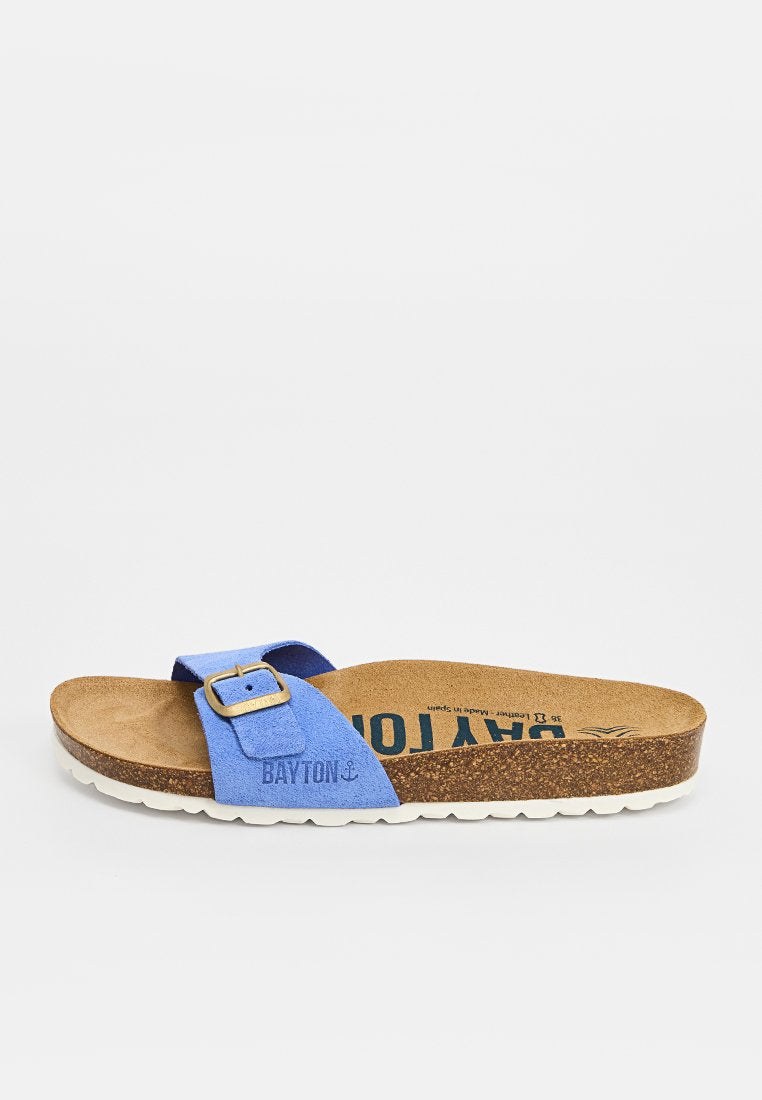 Blaues Wildleder-Pantolette mit verstellbarer Schnalle, Korkfußbett und weißer, strukturierter Sohle, mit "BAYTON" auf Riemen und Fußbett gebrandet.
