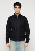 Schwarze Reißverschlussjacke aus strukturiertem Stoff mit Kragen, zwei Fronttaschen und figurbetontem Schnitt. Über einem Rollkragenpullover getragen.