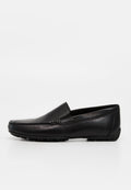 Schwarzer Leder-Slipper mit rundem Zeh, niedrigem Absatz und Gummisohle mit Profil, seitlich auf weißem Hintergrund abgebildet.