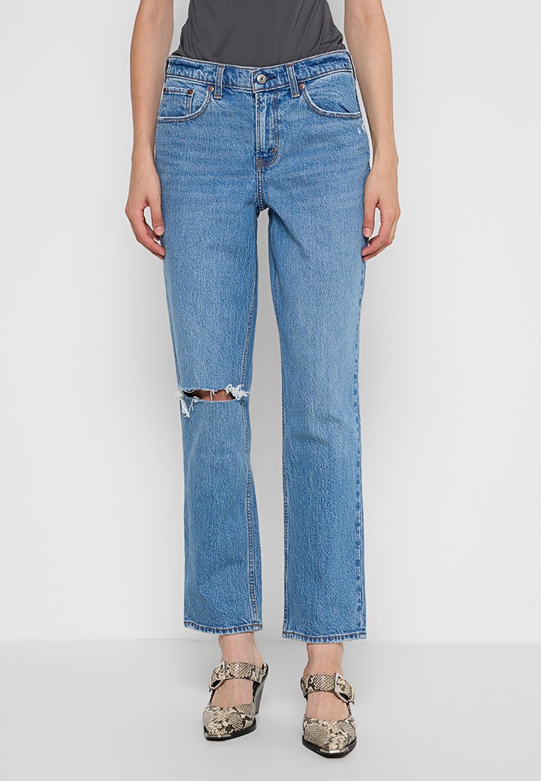 Blaue Denim-Jeans mit geradem Schnitt, ausgestattet mit gestörtem Kniedesign und klassischem Fünf-Taschen-Design. Abgerundet mit einem mittelhohen Bund.