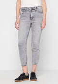 Graue Skinny-Jeans aus Denim mit hoher Taille, ausgestattet mit fünf Taschen, Gürtelschlaufen und Kontrastnähten. Kombiniert mit schwarzen Sneakers.