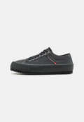 Schwarze Leinenschuhe mit Gummikappe, strukturiertem Stoff, runden Schnürsenkeln und gezackter Sohle. Mit einem kleinen roten Logo der Marke an der Seite.