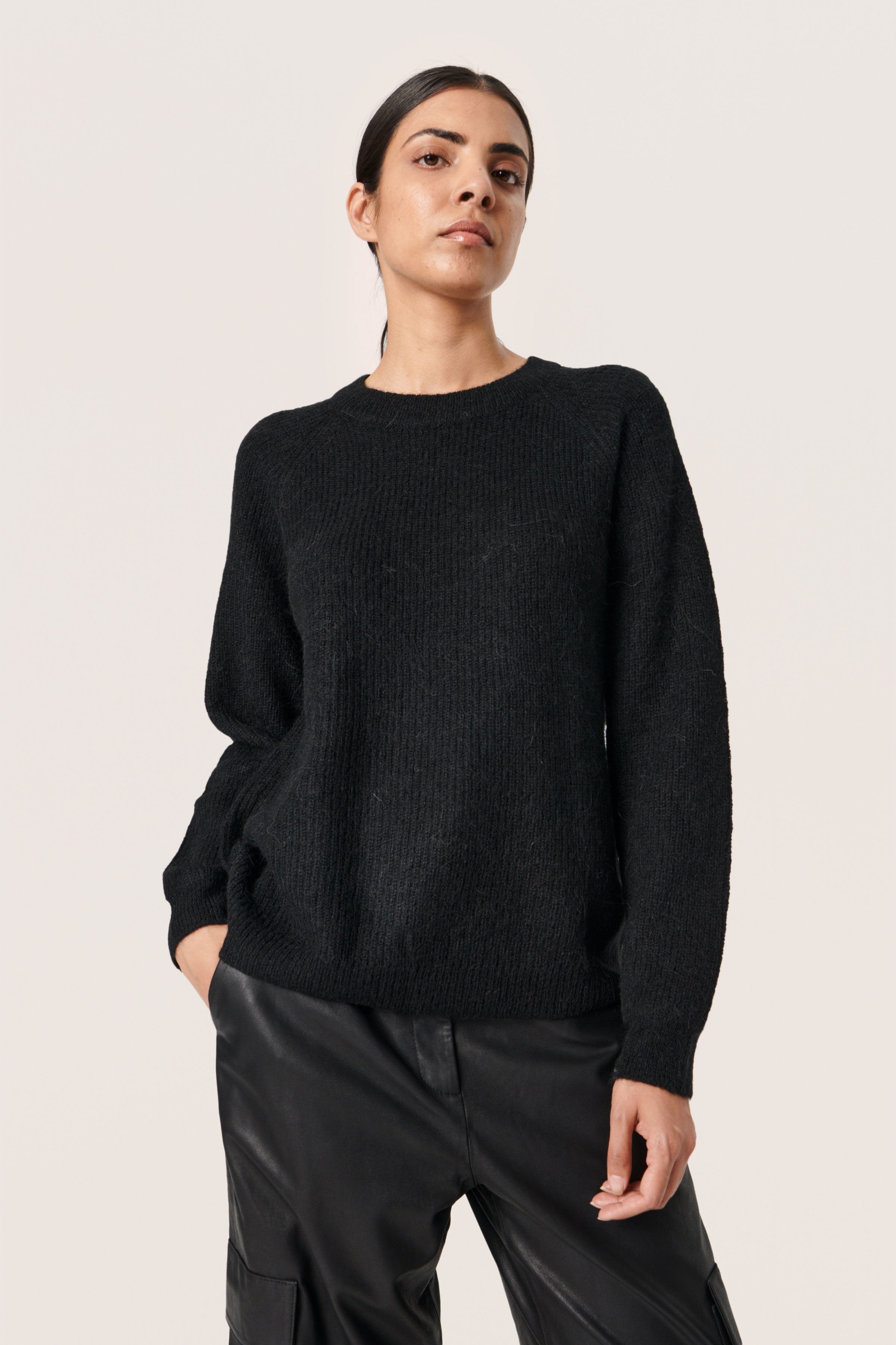Schwarzer, gerippter Pullover mit runder Ausschnitt und überschnittenen Schultern, kombiniert mit schwarzer Lederhose, weich in der Textur und mit lässiger Passform.