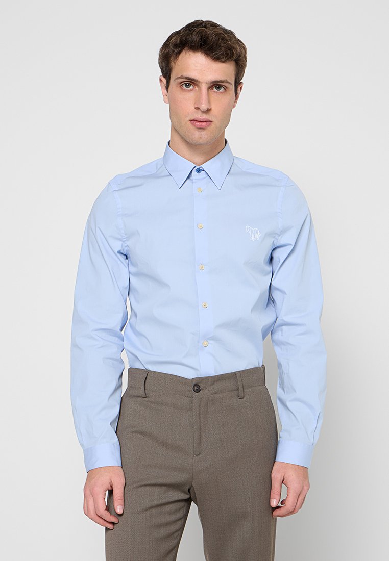 Hellblaues Langarmhemd mit Button-Down-Kragen, goldenen Knöpfen und einem kleinen Stickmuster auf der linken Brust.