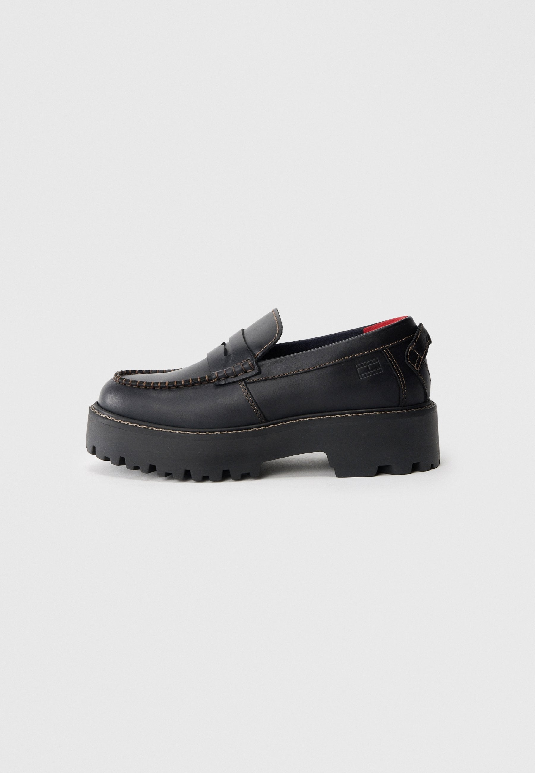 Schwarze Leder-Slipper mit einer dicken, strukturierten Sohle, detaillierten Nähten und einem niedrigen Absatz. Verfügt über eine offene Rückseite und dezentem Branding.
