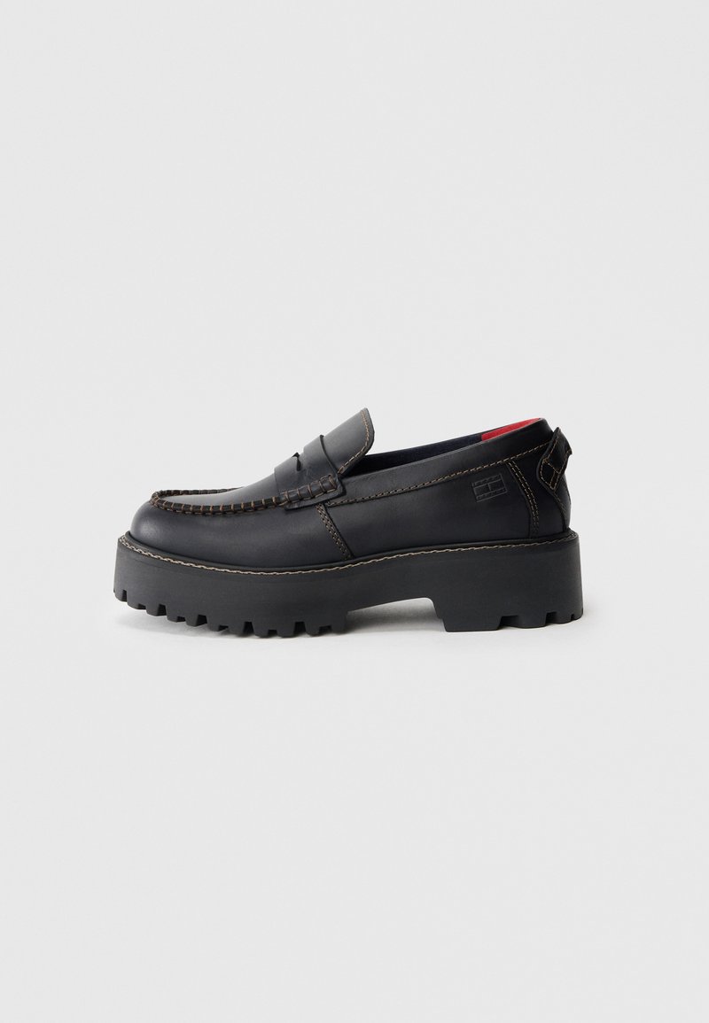 Schwarze Leder-Slipper mit einer dicken, strukturierten Sohle, detaillierten Nähten und einem niedrigen Absatz. Verfügt über eine offene Rückseite und dezentem Branding.