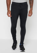 Mann trägt eng anliegende schwarze Sportjogginghosen mit Seitentaschen, Kordelzugbund und schwarze Laufschuhe mit weißen Sohlen.