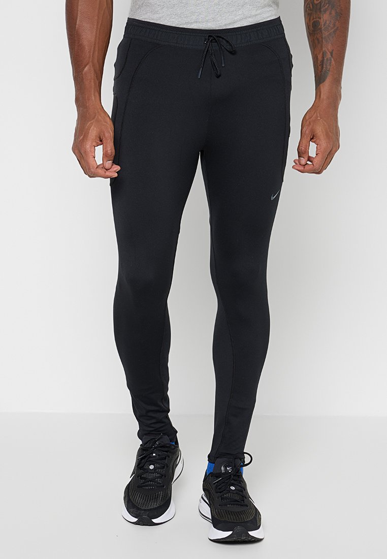 Mann trägt eng anliegende schwarze Sportjogginghosen mit Seitentaschen, Kordelzugbund und schwarze Laufschuhe mit weißen Sohlen.