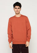 Langärmliges Sweatshirt in Rostfarbe aus weicher Baumwolle, mit rundem Ausschnitt, gerippten Bündchen und einem dezenten, eingeprägten Logo auf der Brust.