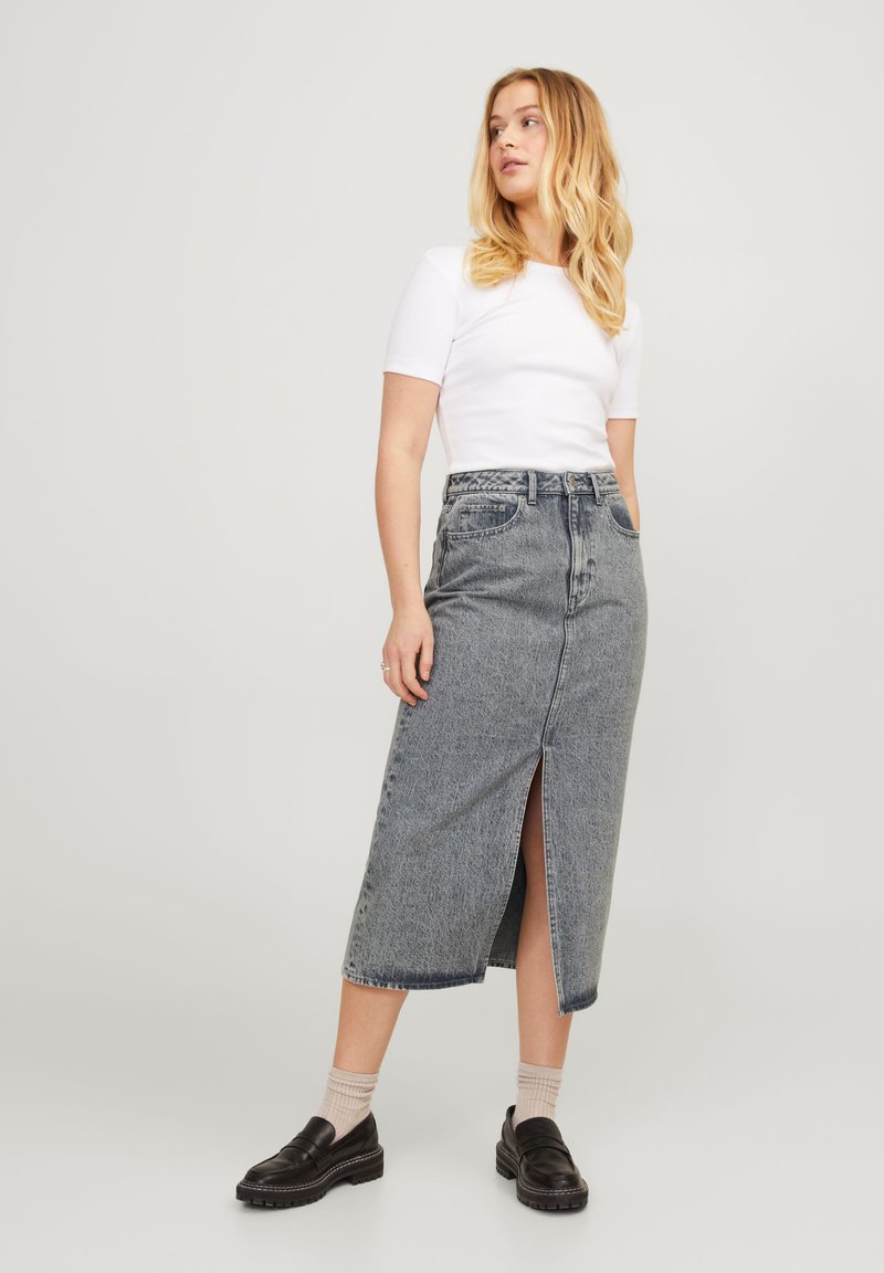 Jeans-Midi-Rock in verblasstem Grau mit einem Schlitz vorne, hoher Taille, Gürtelschlaufen und klassischem Fünf-Taschen-Design. Getragen mit einem enganliegenden weißen Oberteil.