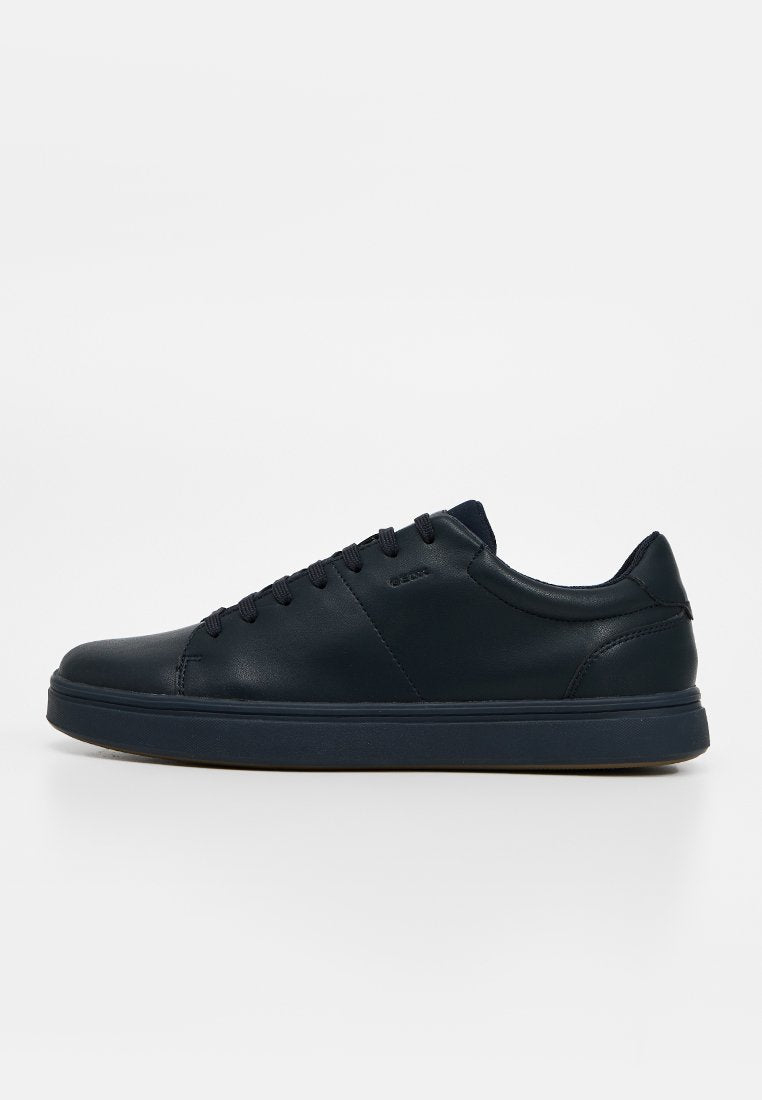 Schwarzer niedriger Ledersneaker mit Schnürsenkeln, flacher Sohle und minimalen Nahtdetails auf weißem Hintergrund.