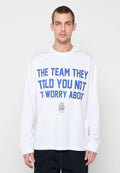 Weißes Langarm-T-Shirt mit blauem fettem Text "THE TEAM THEY TOLD YOU NOT TO WORRY ABOUT" und kleinen Logos auf der unteren Vorderseite.