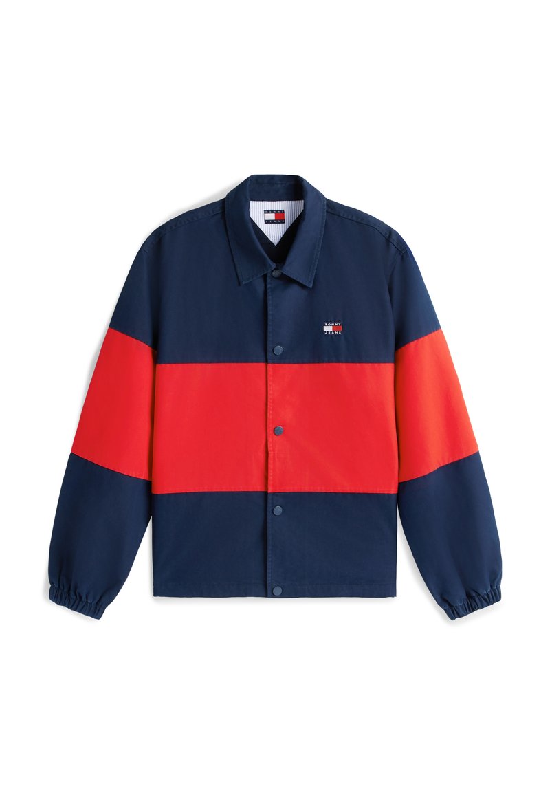 Marineblaue und rote Trainerjacke mit Druckknöpfen, elastischen Bündchen und kleinem Tommy Jeans-Logo auf der linken Brust.