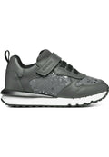 Graue Sneakers mit einem Obermaterial aus Leder, Netzdetails, elastischen Schnürsenkeln und einem Klettverschlussriemen. Sie besitzen eine strukturierte Gummisohle und dezente Akzente.
