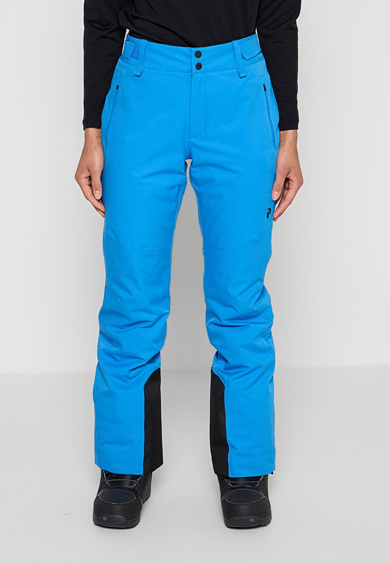 Helle blaue Schneehose mit schwarzen verstärkten Bündchen, getragen mit schwarzen Stiefeln und einem schwarzen Langarm-Oberteil, Vorderansicht von der Taille bis zu den Füßen.