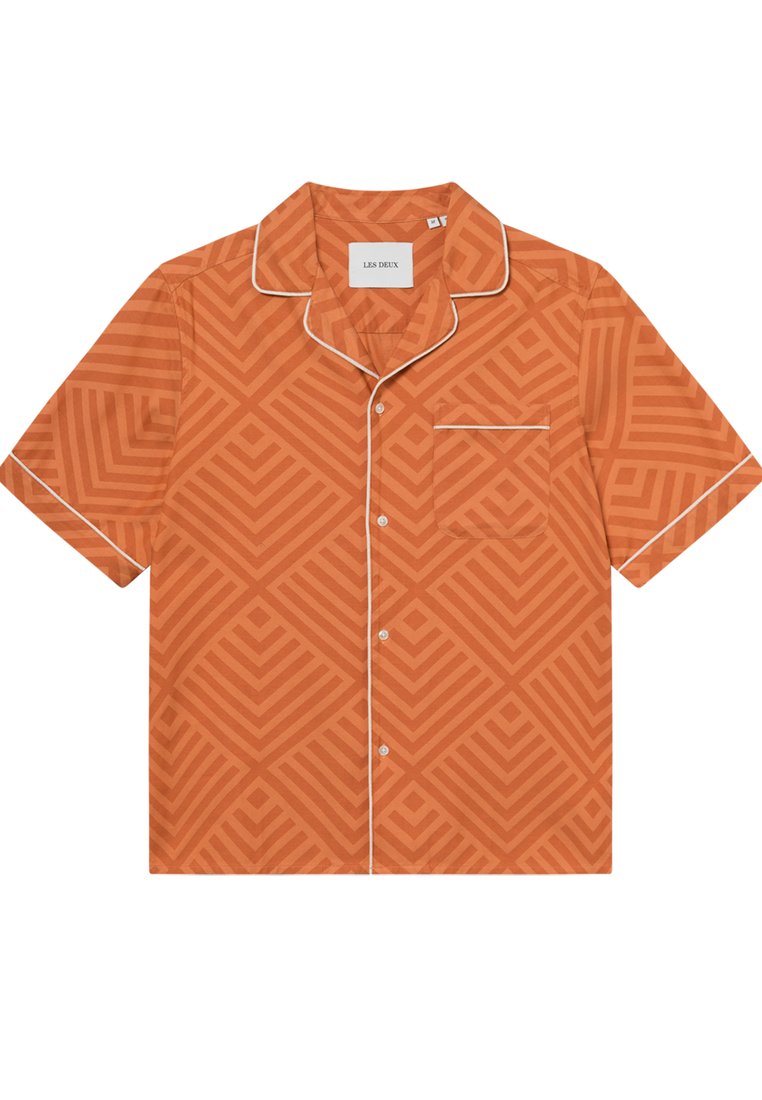 Kurzärmliges, oranges Shirt mit geometrischem Muster. Weiße Borte entlang des Kragens und der Tasche. Hergestellt aus leichtem Stoff.