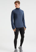 Mann trägt einen navyblauen Langarm-Reißverschlussoberteil, schwarze Shorts über schwarzen Leggings und graue Laufschuhe, steht vor einem weißen Hintergrund.