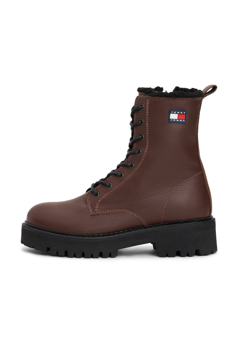 Braune Lederstiefelette mit schwarzem Kunstfellkragen, runder Zehenform, schwarzem Gummisohle und schwarzen Schnürsenkeln. Verfügt über ein Logopatch an der Seite.